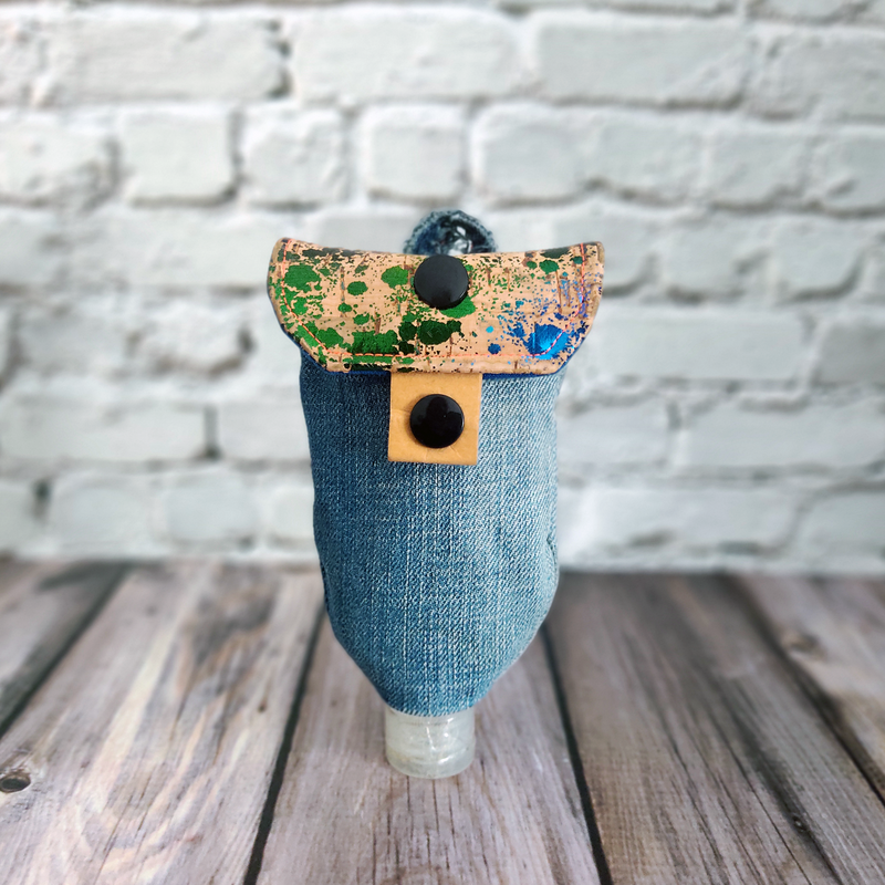 Frontansicht einer Upcycling-Tasche für Desinfektionsmittel, genäht aus alter Jeans und neuem Korkstoff. Die Tasche ist mit einem schwarzen Druckknopf geschlossen.